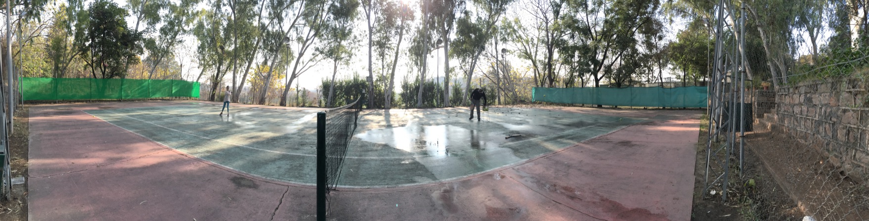 Two members playing doubles on the clay court in morning light