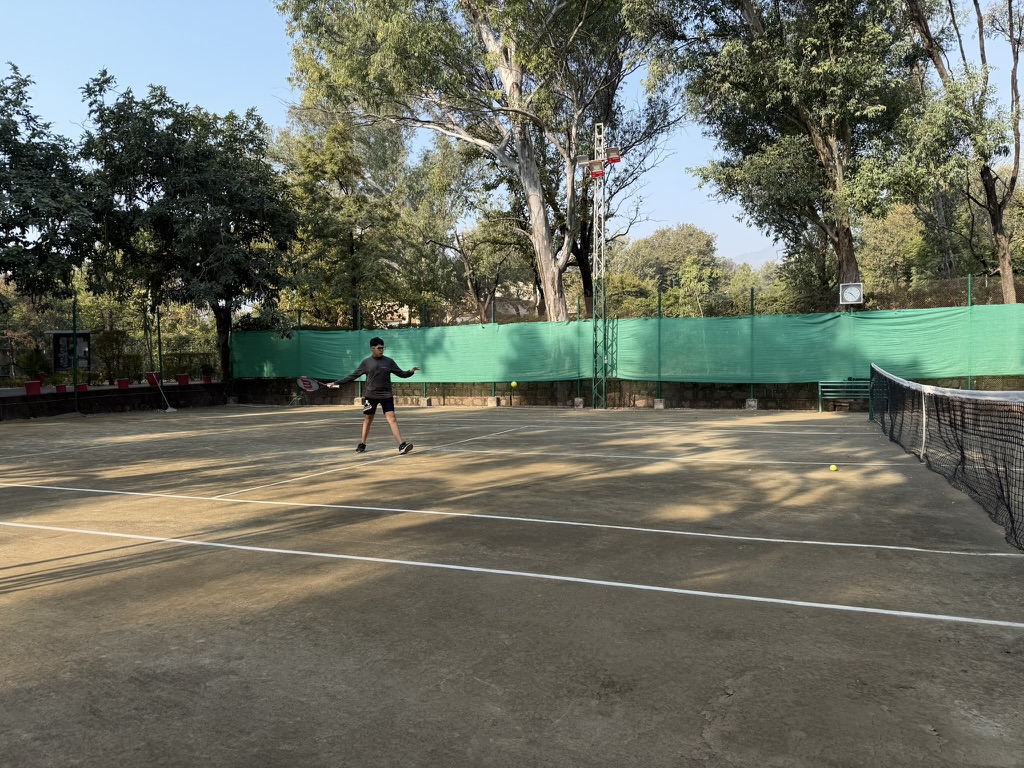 Coach working with a junior player on the hard court